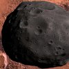 Der Marsmond Phobos ist noch 20 km entfernt und bedeckt soeben das Arsinoes Chaos der Valles Marineris. Ein kleiner Asteroid (rechts unten) begleitet ihn.